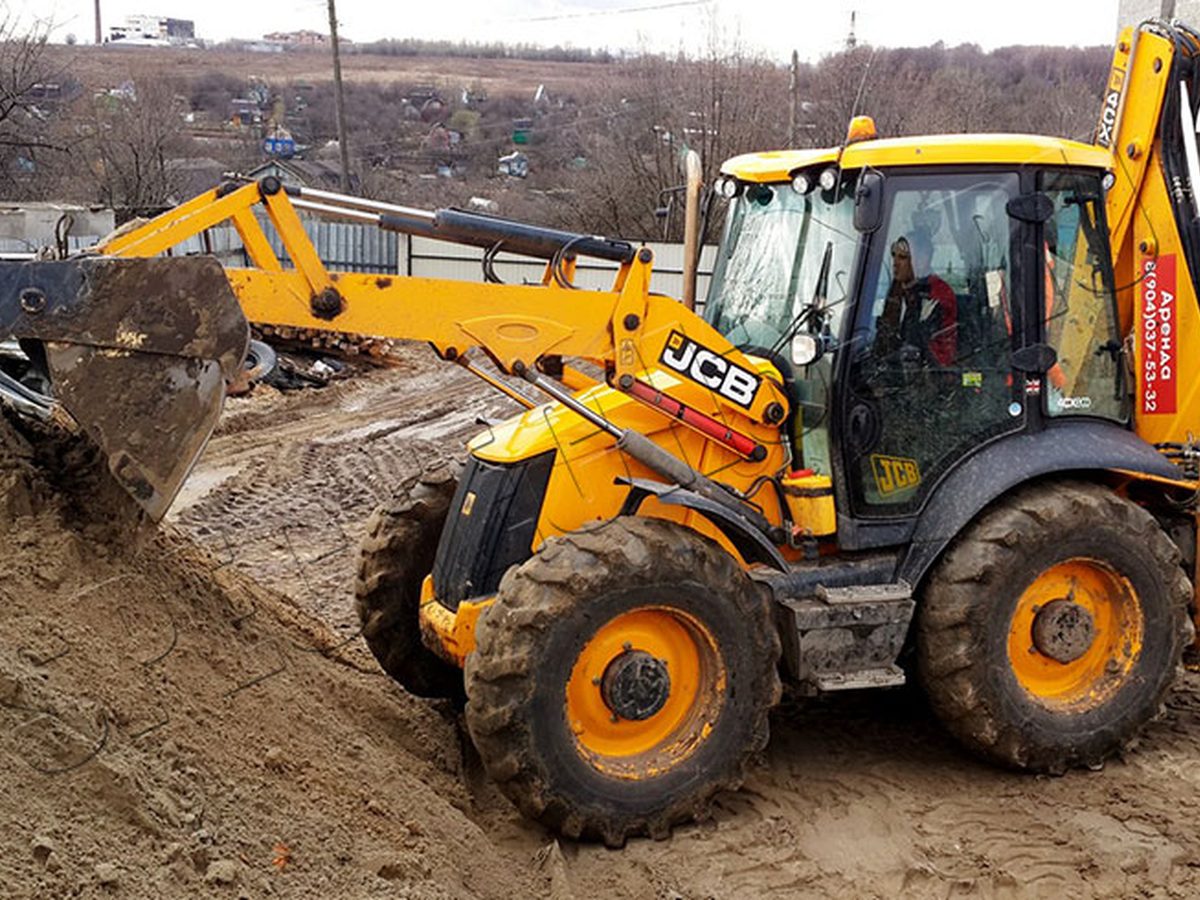 Экскаватор-погрузчик JCB копает траншею на строительной площадке